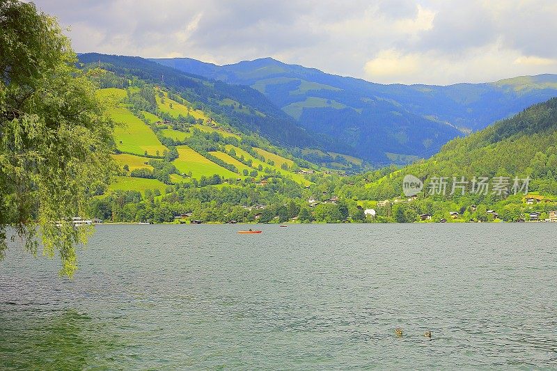 孤独的红船漂浮在美丽的泽勒湖上-泽尔am See和山脉景观，Tirol风景在奥地利萨尔茨堡土地，奥地利